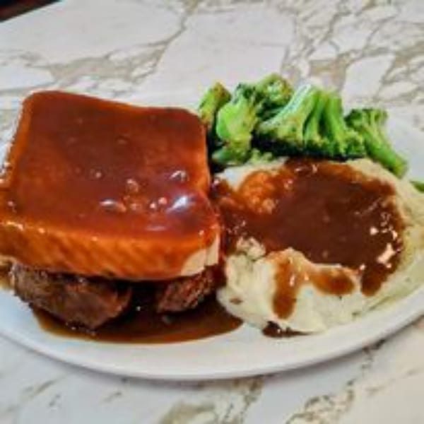 Hot roast beef sandwich with gravy, mashed potatoes, and broccoli on a white plate.