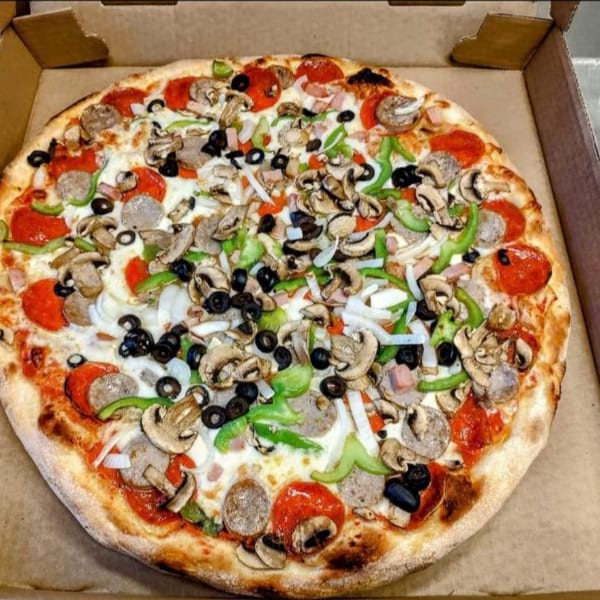 A Gus' Red Hots pizza in a box, topped with pepperoni, sausage, mushrooms, olives, and peppers.